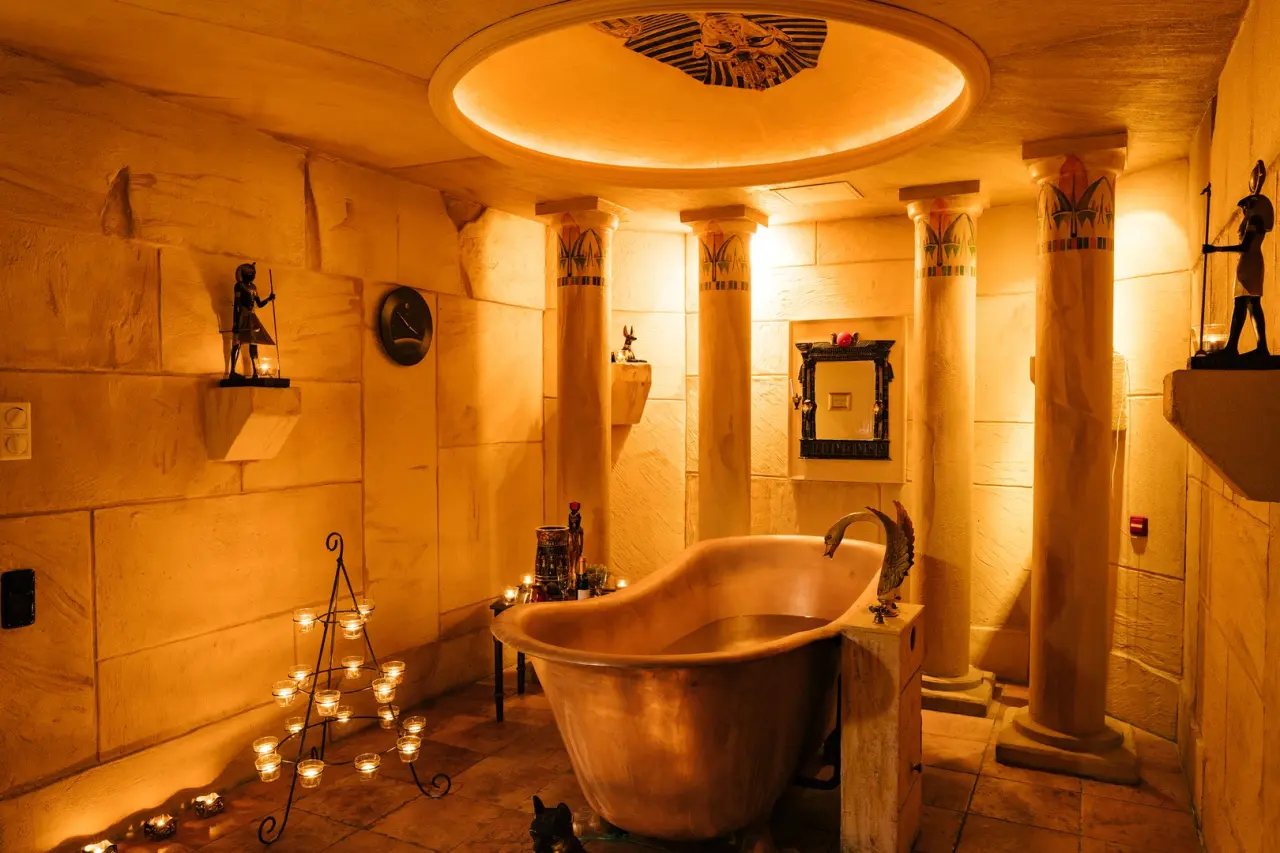 Ägyptisch inspiriertes Badezimmer mit Kupferwanne, Säulen und Kerzenlicht im TRIHOTEL Rostock.