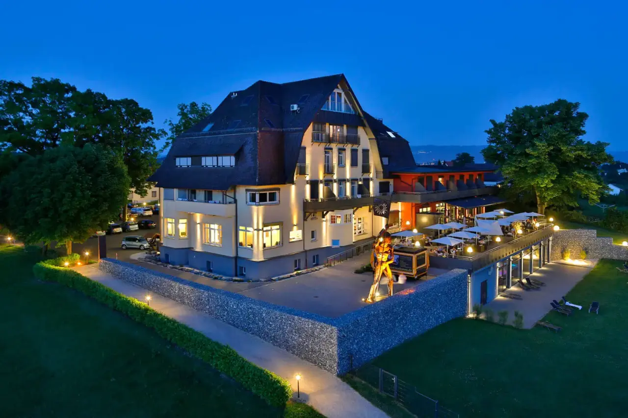 Abendansicht des Bodensee-Hotel Sonnenhof mit beleuchteter Fassade, Restaurant-Terrasse und Garten.