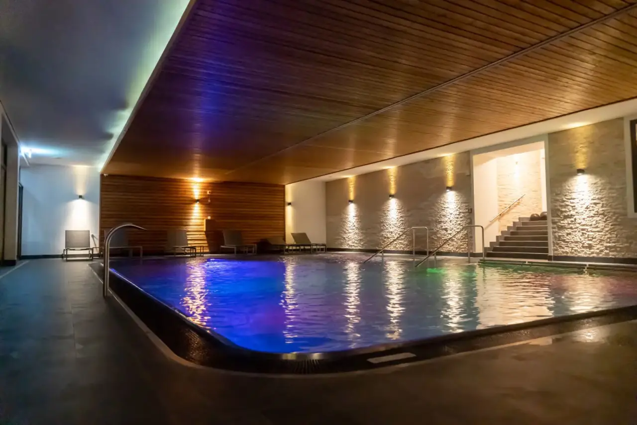 Modernes Hallenbad mit farbiger Beleuchtung, Holzdecke und Liegen im Bodensee-Hotel Sonnenhof
