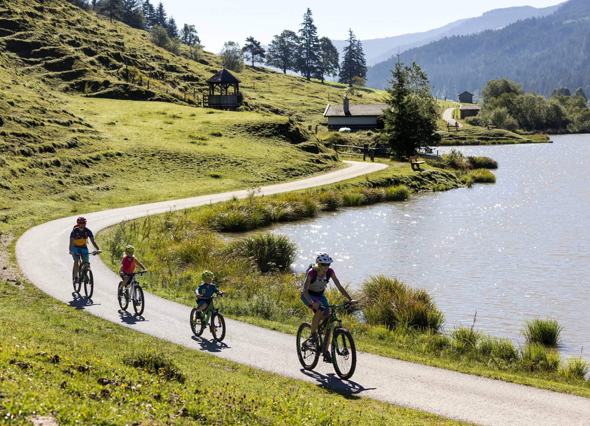 Naturhotel Forsthofgut in Leogang – Familie beim Radfahren am malerischen See | Wellnesshotel Salzburger Land