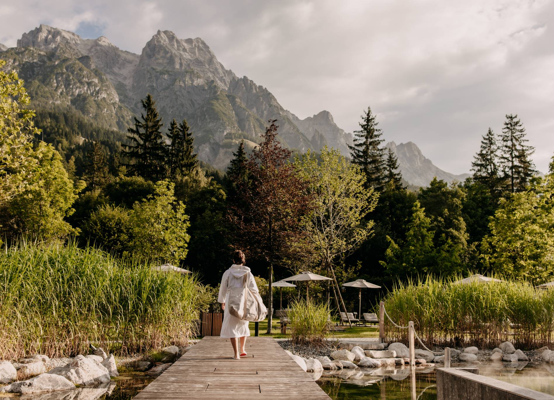 Naturhotel Forsthofgut in Leogang – Frau im Bademantel auf Holzsteg mit Bergblick | Wellnesshotel Salzburger Land