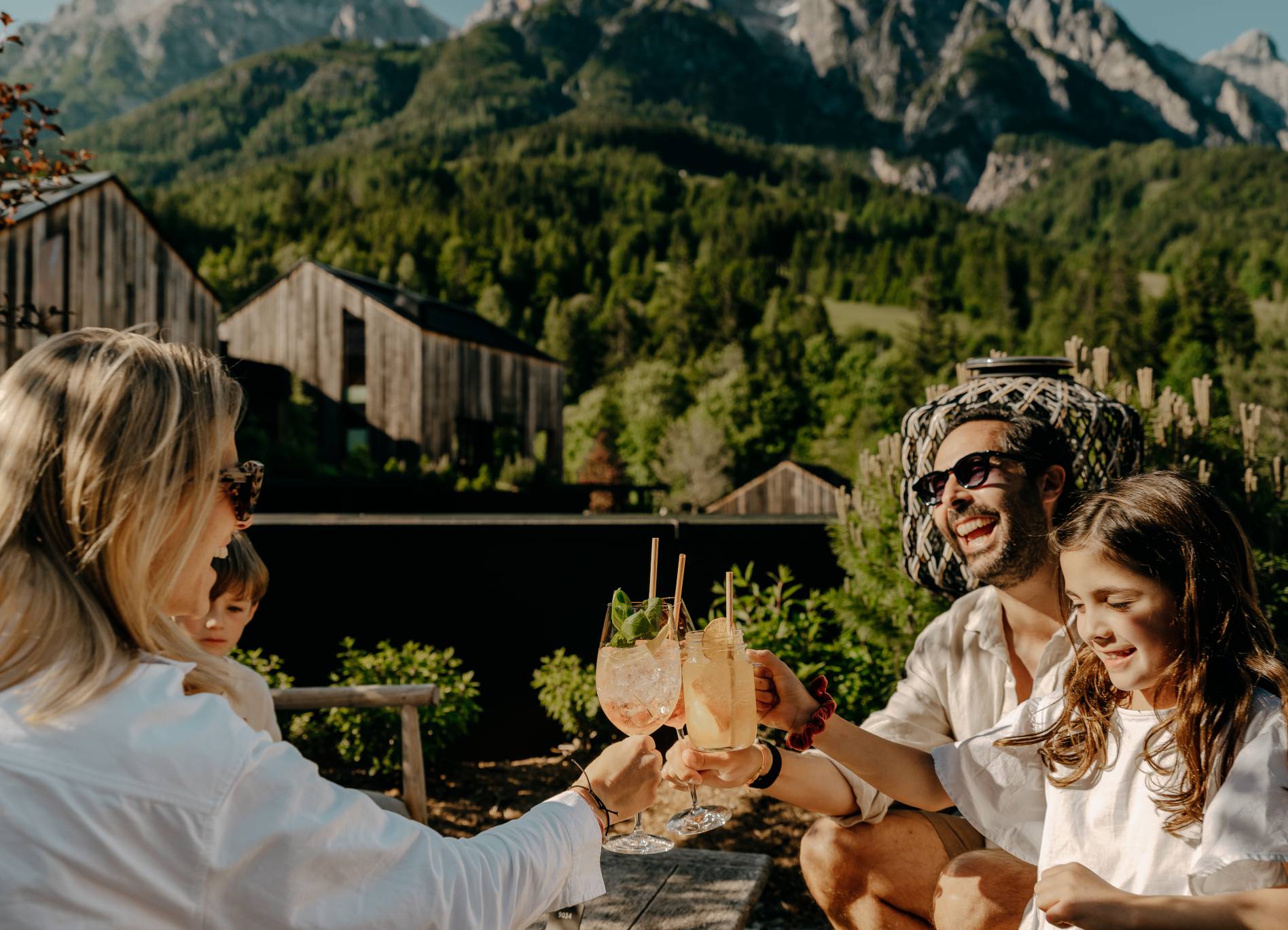 Naturhotel Forsthofgut in Leogang – Familie stößt mit erfrischenden Getränken im Garten an | Wellnesshotel Salzburger Land