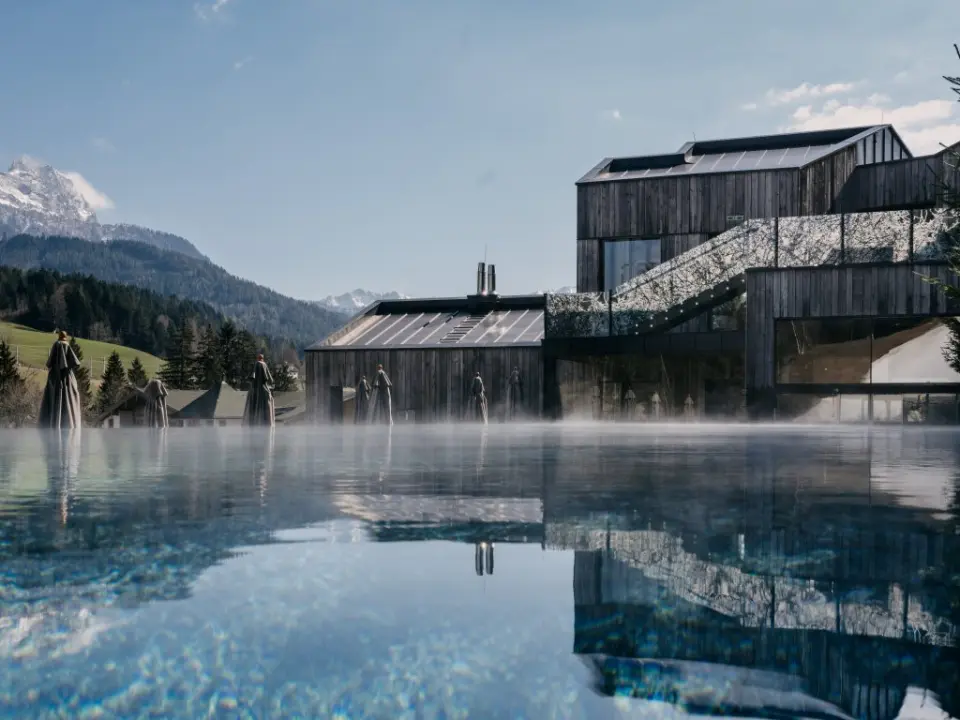 Beheizter Infinity Pool mit Dampf und Bergpanorama am Naturhotel Forsthofgut. Moderne Architektur und Alpenblick.