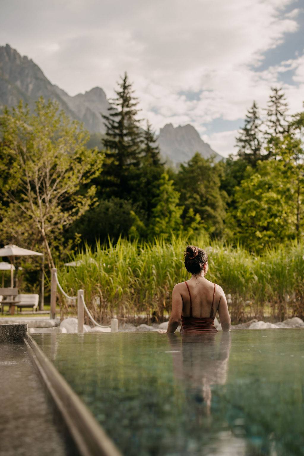 Naturhotel Forsthofgut in Leogang – Frau entspannt im Außenpool mit Blick auf die Natur | Wellnesshotel Salzburger Land