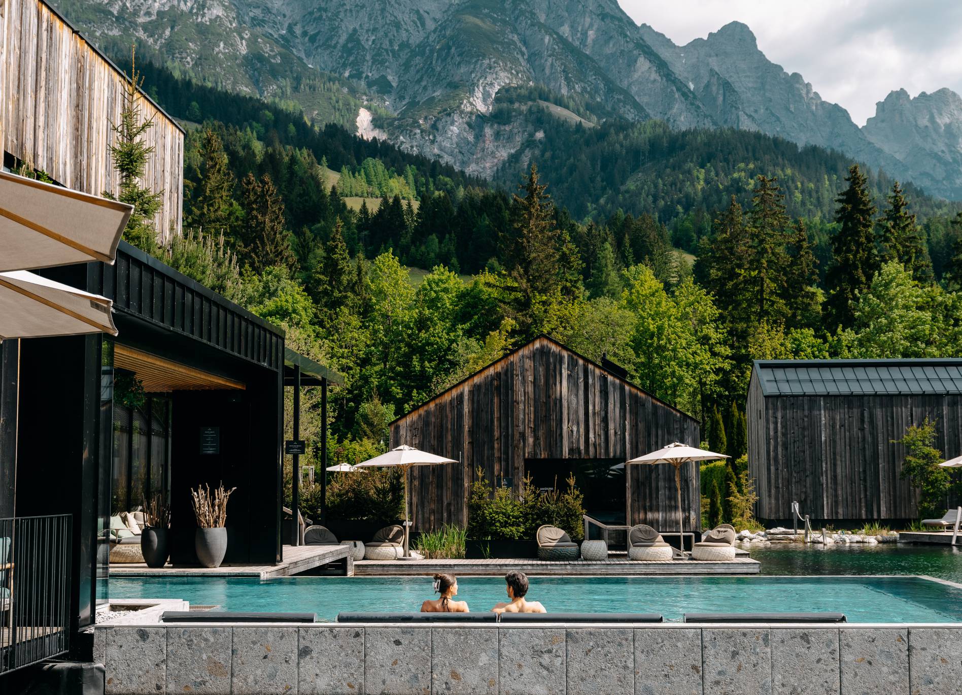 Naturhotel Forsthofgut in Leogang – Paar im Infinity-Pool mit beeindruckendem Bergpanorama | Wellnesshotel Salzburger Land
