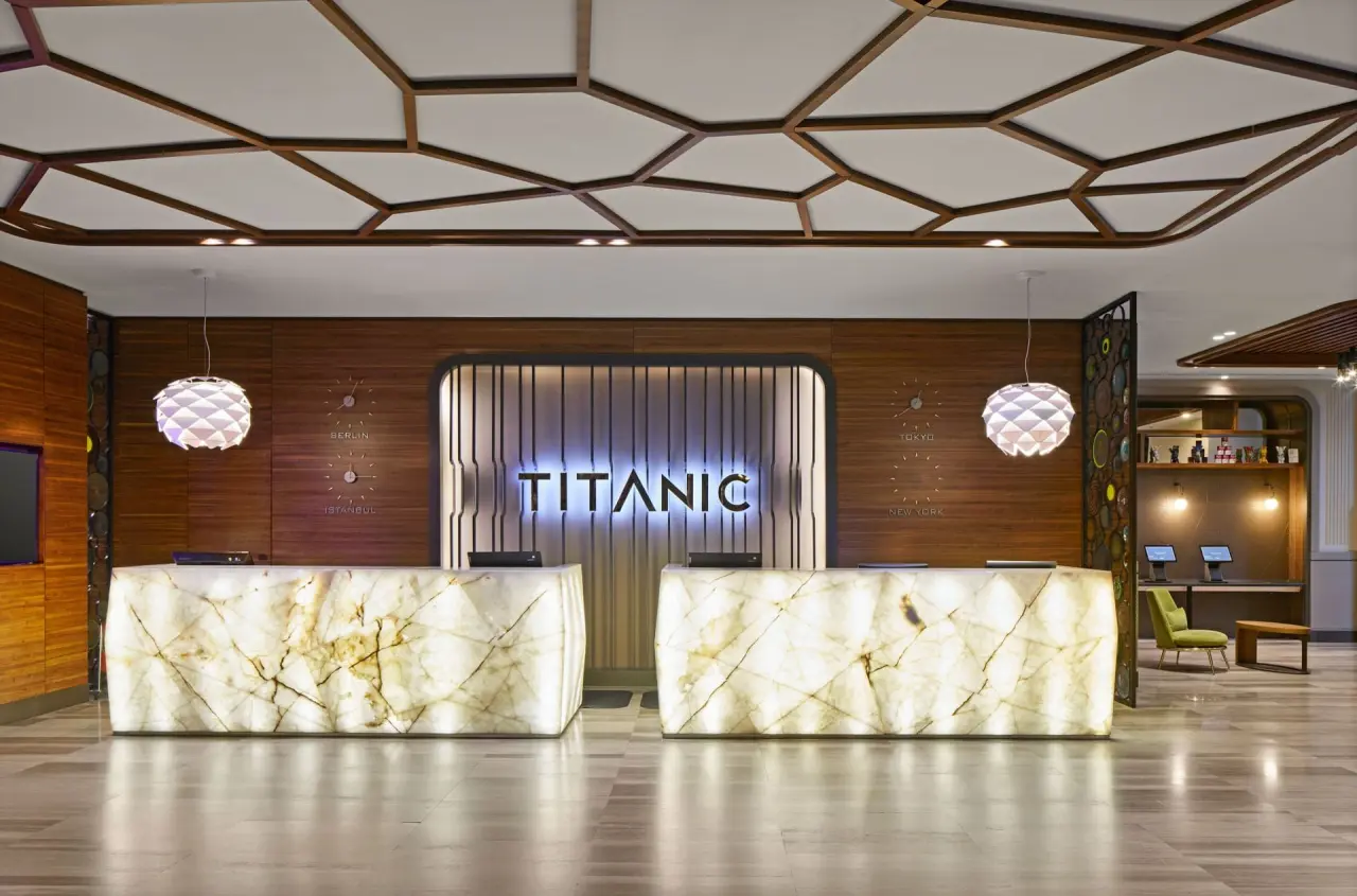 Moderne Hotel-Lobby des Titanic Chaussee Berlin mit beleuchteten Rezeptionstheken und stilvoller Deckenbeleuchtung.