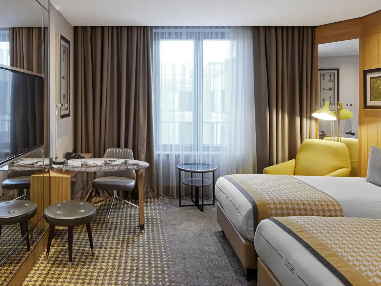 Modernes Hotelzimmer mit zwei Einzelbetten, Schreibtisch und Sessel im Titanic Chaussee Berlin.