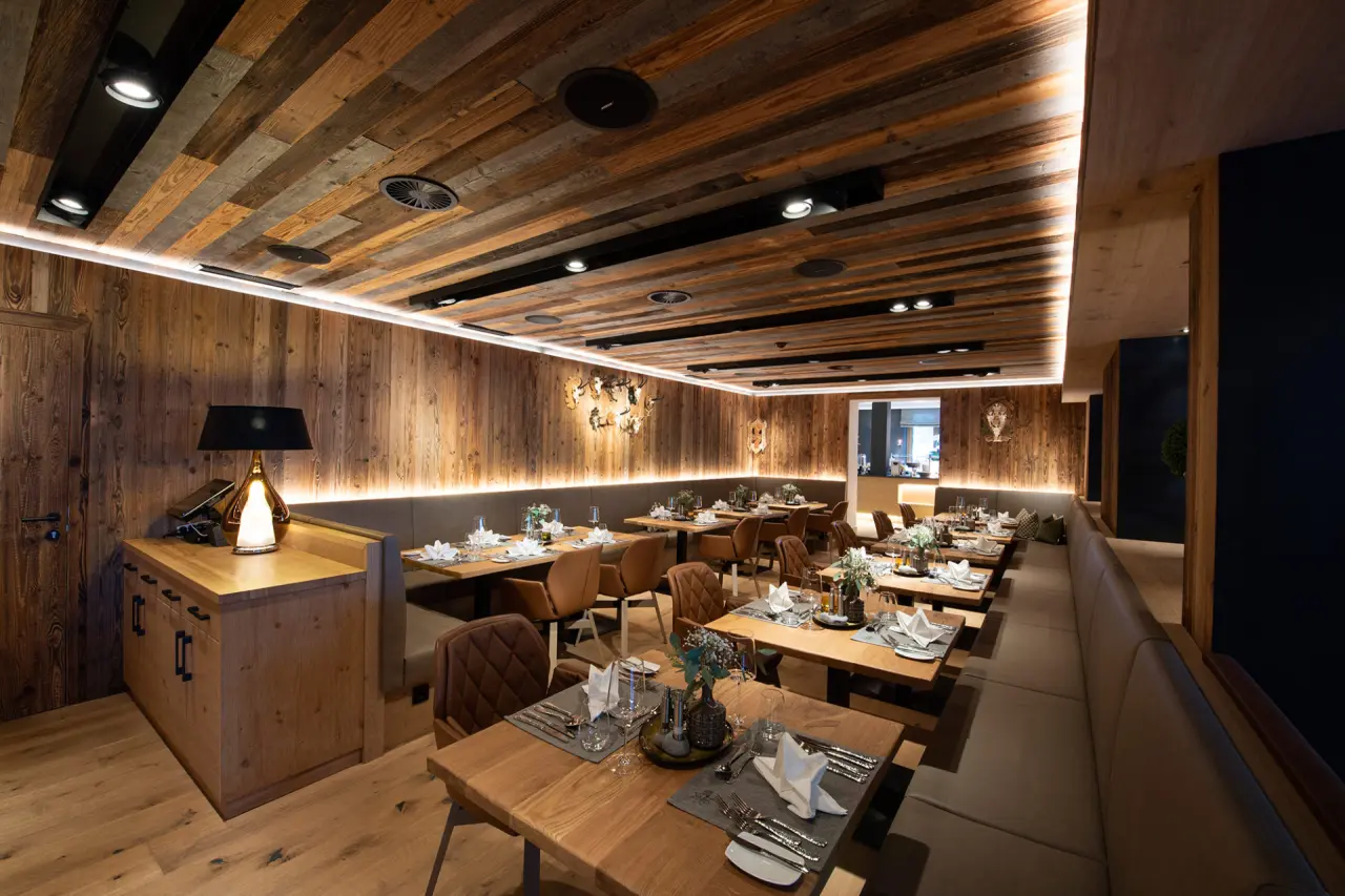 Gemütliches Restaurant im alpinen Stil mit Holzelementen und elegant gedeckten Tischen im Hotel Edelweiss.