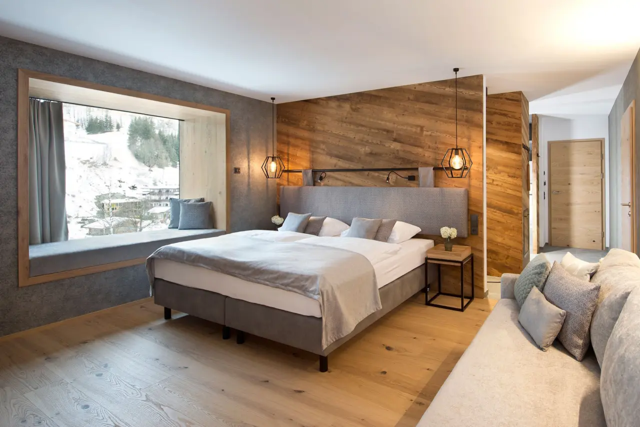 Modernes Hotelzimmer im Hotel Edelweiss mit gemütlichem Bett, Fensterbank und Bergblick im Winter.