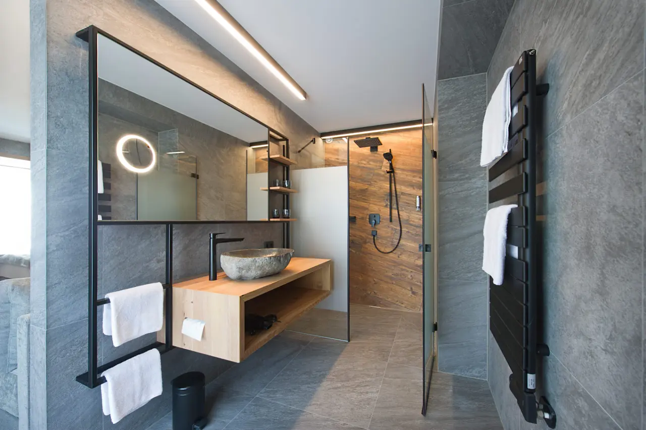 Modernes Badezimmer mit Natursteinwaschbecken und Regendusche im Hotel Edelweiss.