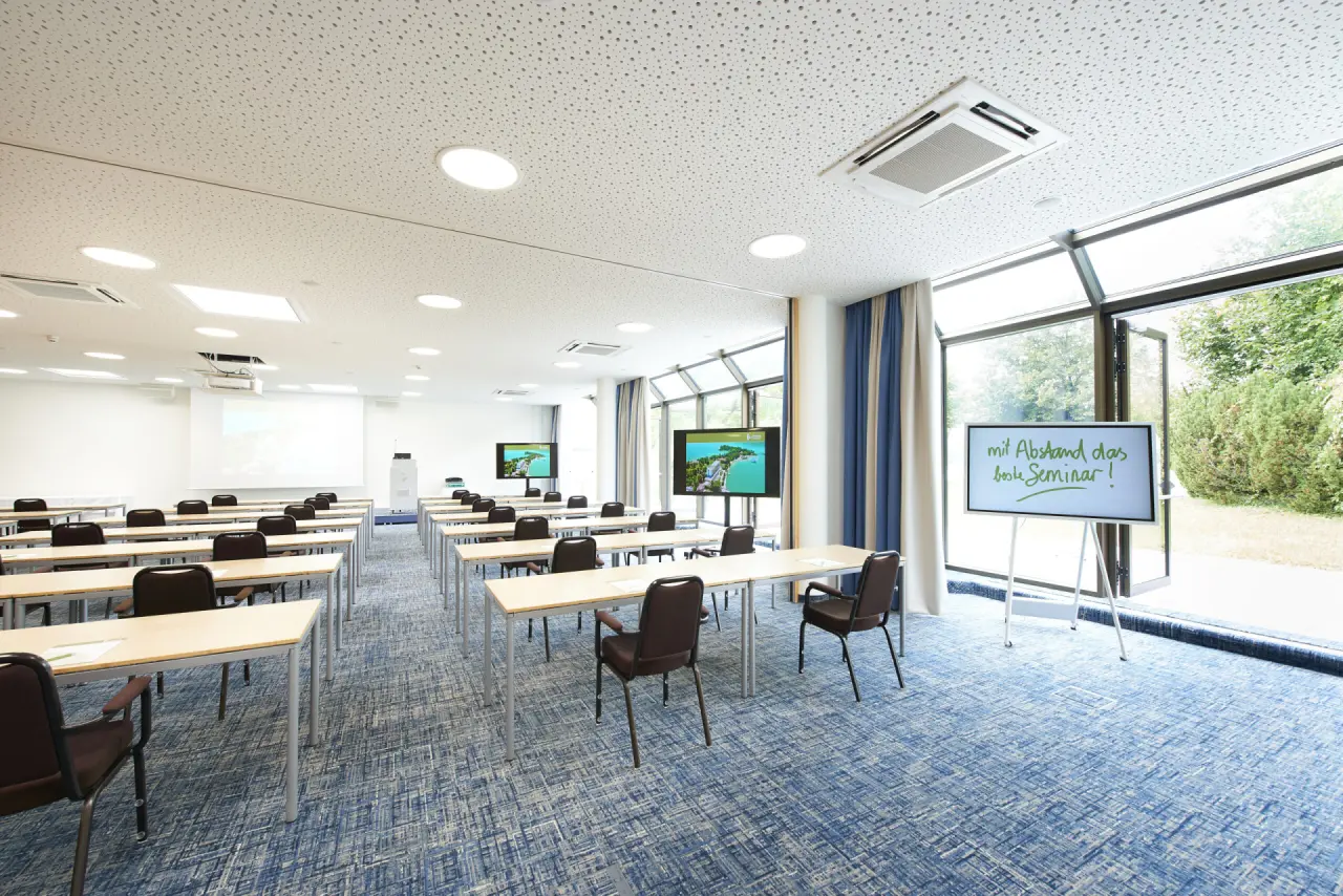 Modern ausgestatteter Seminarraum im Parkhotel Pörtschach mit Tischen, Stühlen und Bildschirmen für Konferenzen.