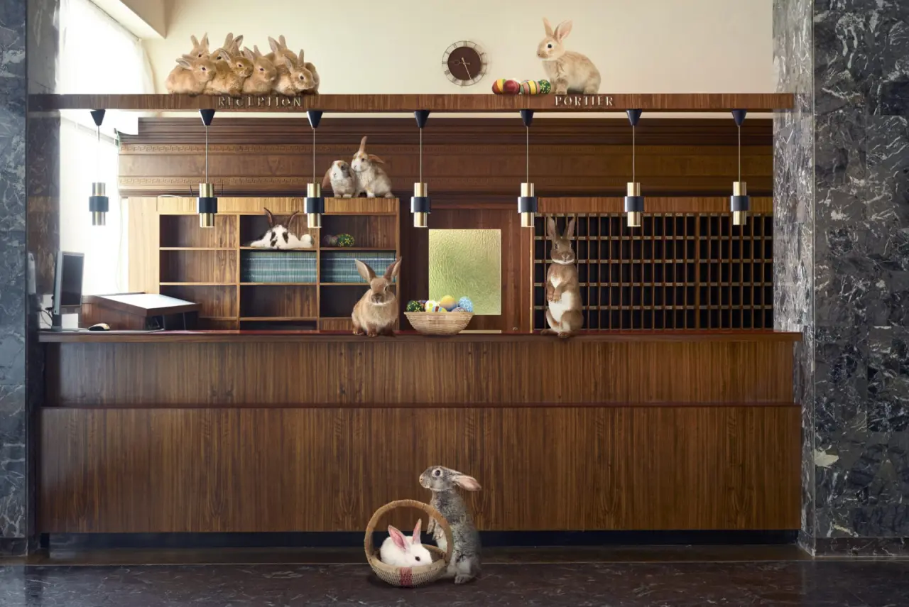 Osterdekoration mit zahlreichen Hasen an der Rezeption des Parkhotel Pörtschach. Warme Holztheke und Marmorakzente in der Lobby.