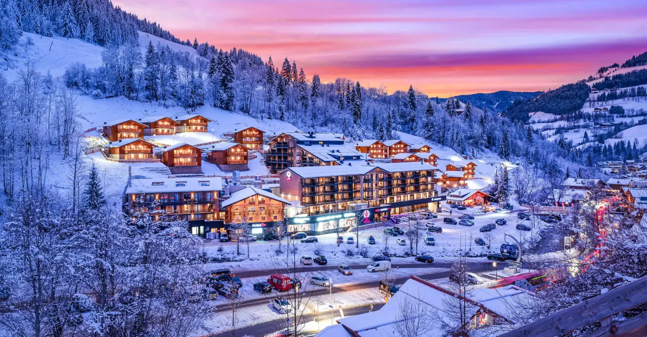 Winterliches Hotel Adapura Wagrain bei Sonnenuntergang, umgeben von verschneiten Bergen und beleuchteten Gebäuden.