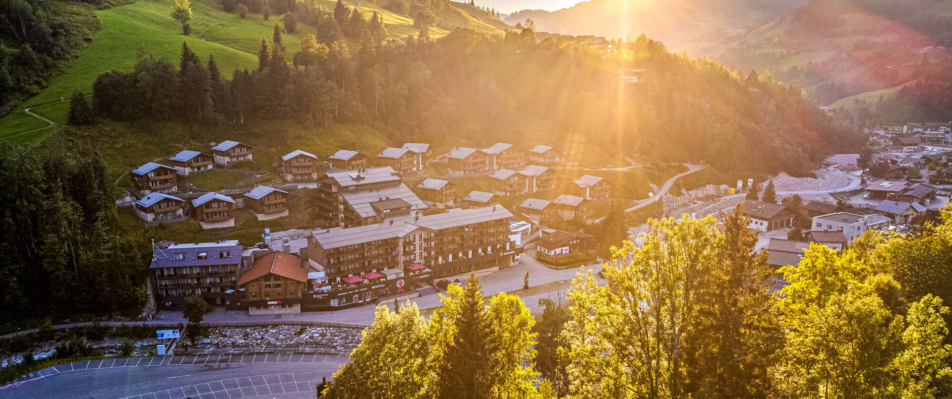 Hotel Adapura Wagrain in Wagrain – Hotelanlage im Sommer mit Sonnenstrahlen | Wellnesshotel Salzburger Land