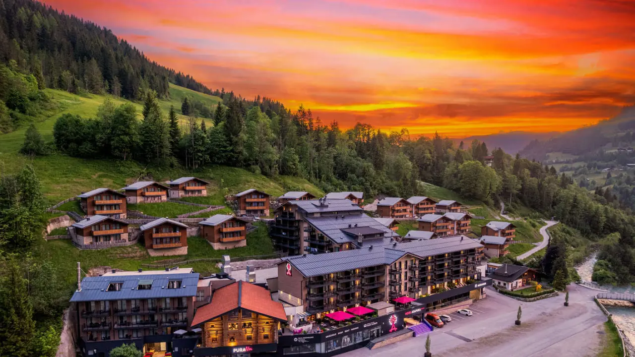 Panoramablick auf das Hotel Adapura Wagrain und seine Chalets bei Sonnenuntergang in den österreichischen Alpen.