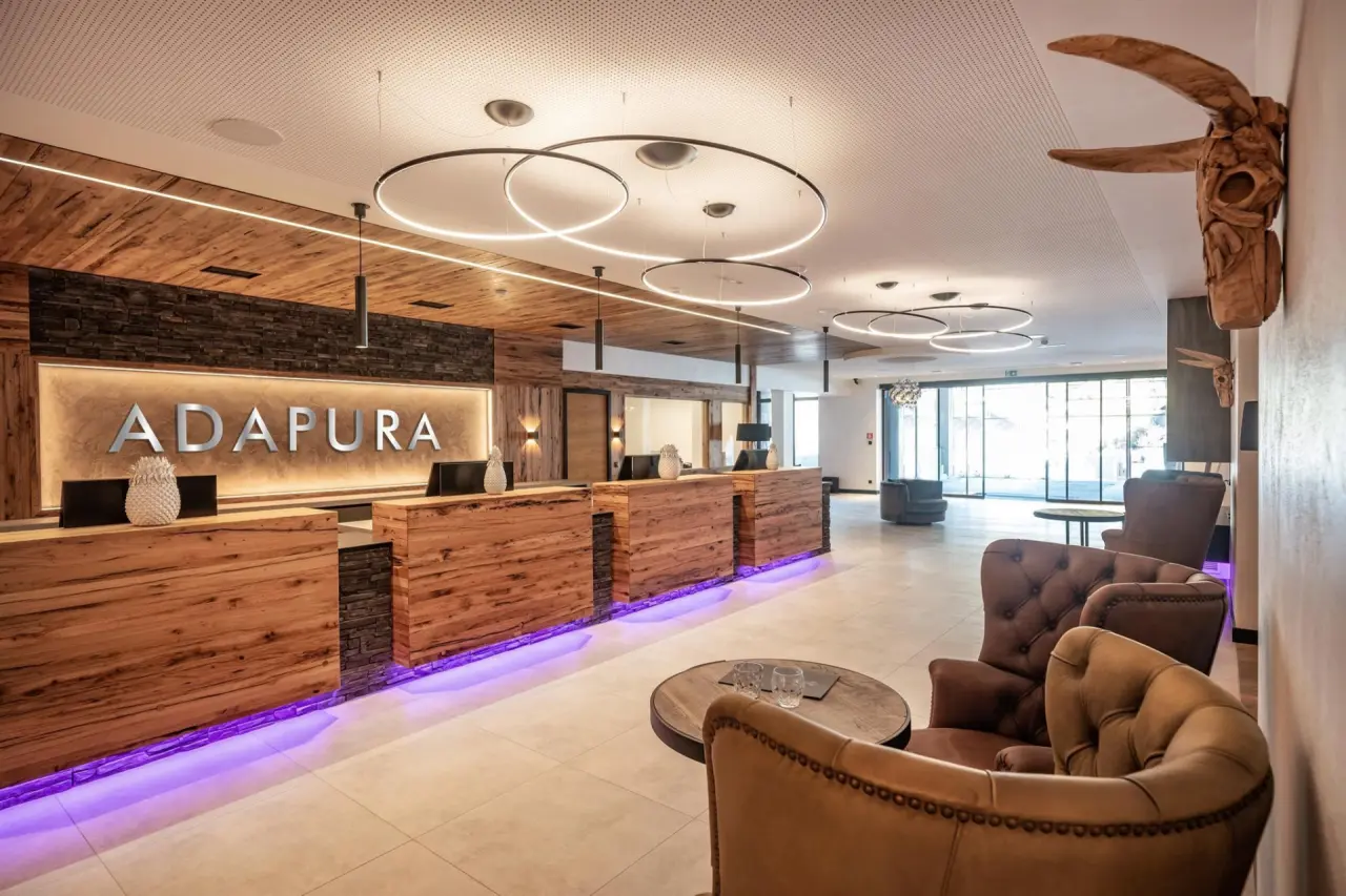 Moderne Rezeption und Lobby des Hotel Adapura Wagrain mit Holzdesign, Steinakzenten und stilvoller Beleuchtung.