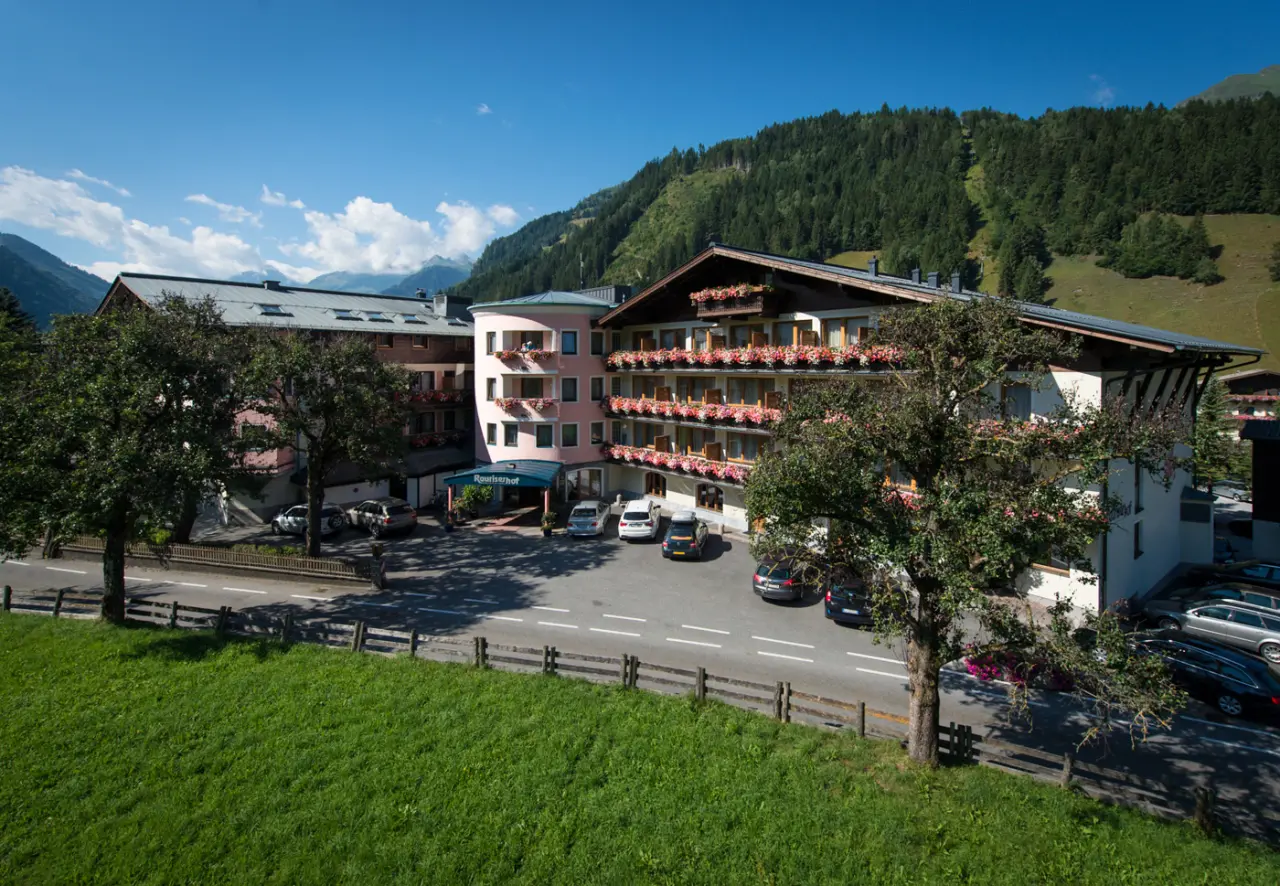 Hotel Rauriserhof in den Alpen mit blühenden Balkonen und Bergpanorama unter blauem Himmel.