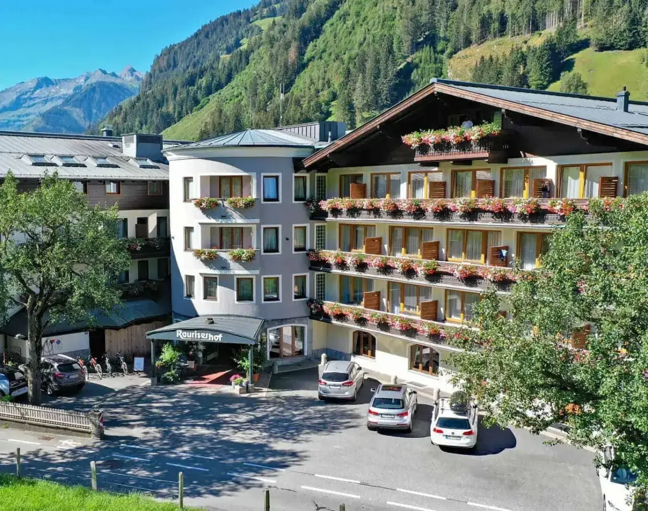 Aussenansicht des Hotel Rauriserhof mit blühenden Balkonen vor einer beeindruckenden Bergkulisse im Raurisertal.