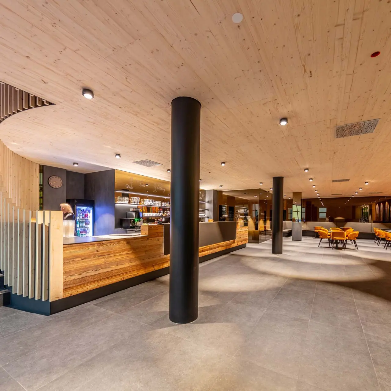 Moderne Hotelbar und Loungebereich mit Holzakzenten und orangefarbenen Sesseln im Fair Hotel.