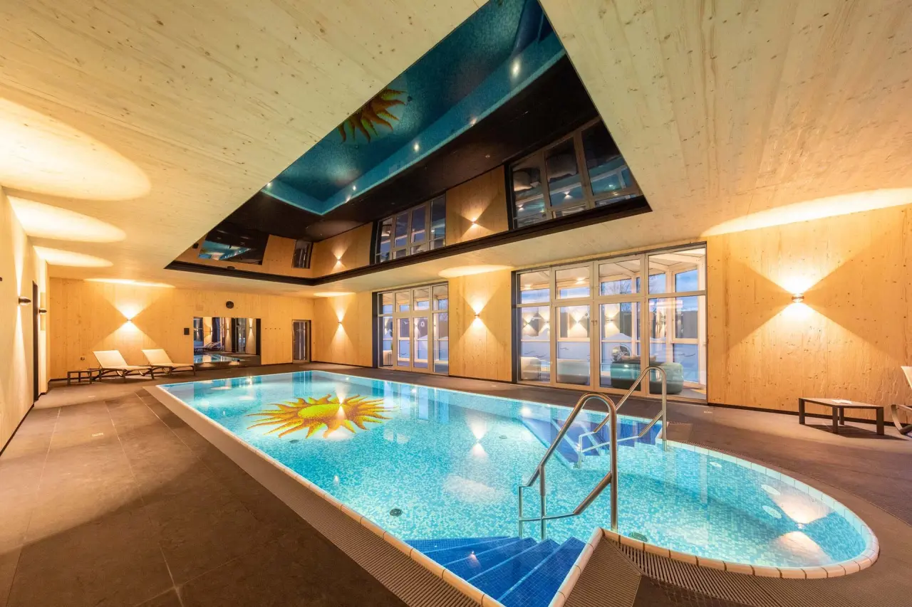 Grosszügiger Innenpool mit Sonnen-Mosaik und Holzdesign im Fair Hotel. Entspannung pur im Wellnessbereich.