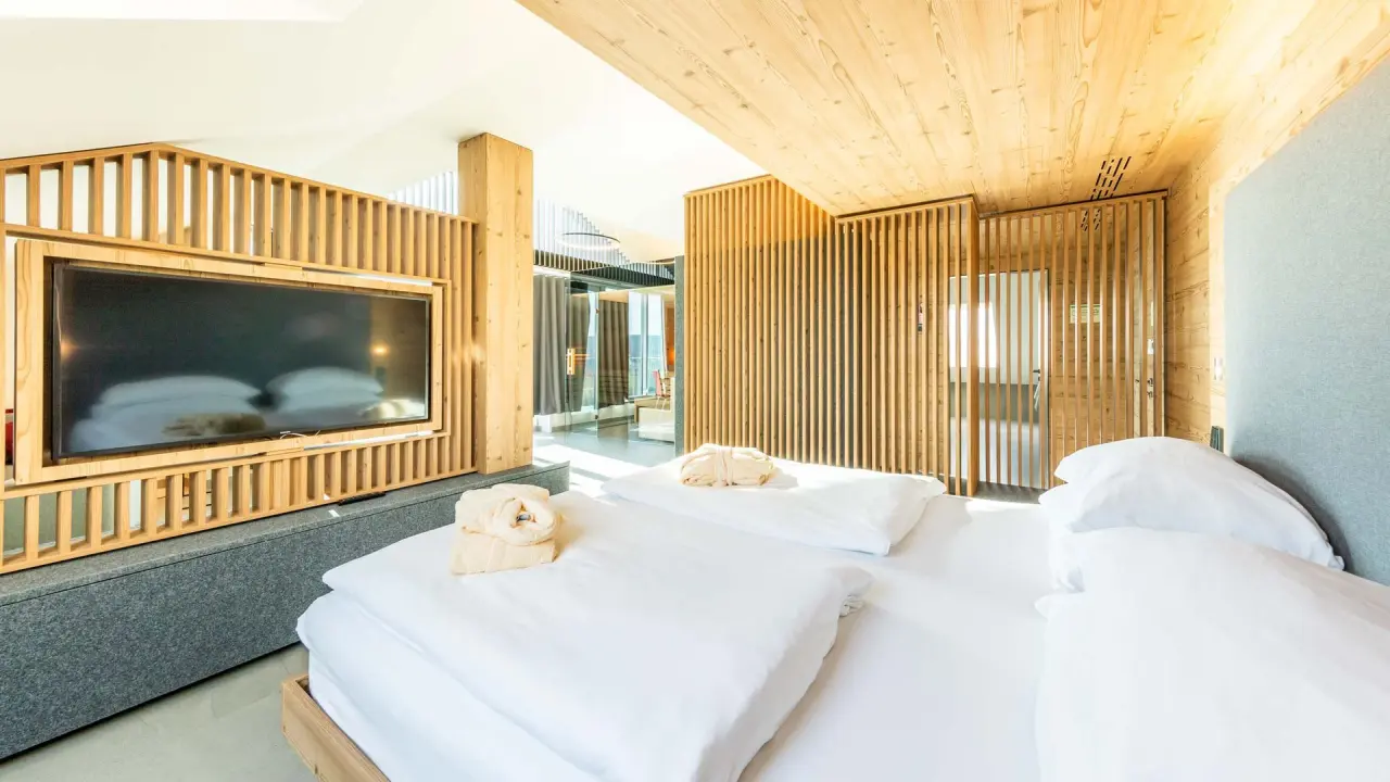Modernes Doppelzimmer im Fair Hotel mit heller Holzvertäfelung, großem TV und Bademänteln für einen erholsamen Aufenthalt.