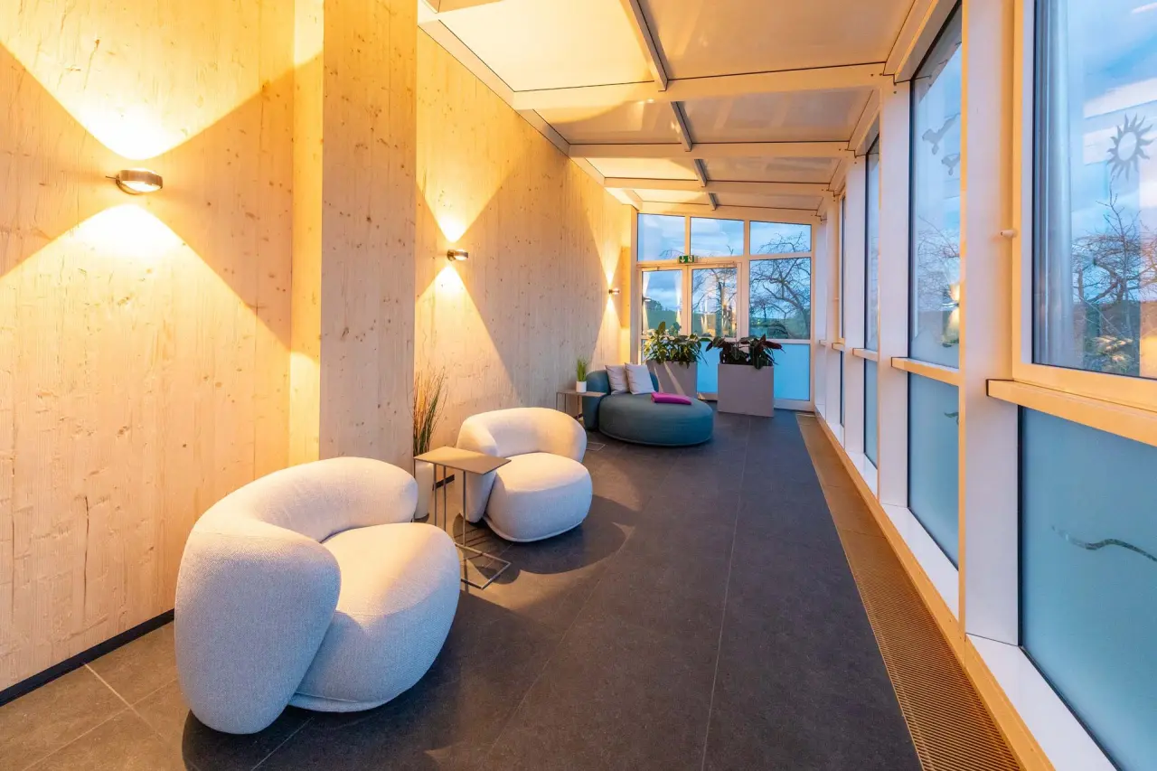 Moderner Ruheraum im Fair Hotel mit bequemen Loungemöbeln, Holzwänden und großen Fenstern für entspannte Momente.