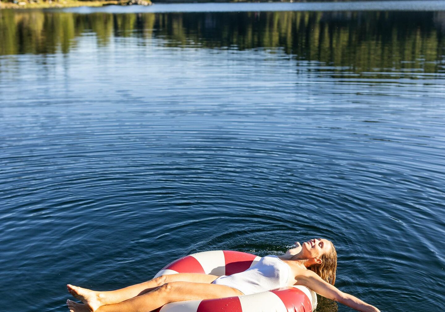 Hotel Hochschober in Turracher Höhe – Frau entspannt auf einem Schwimmring im klaren Bergsee | Wellnesshotel Kärnten