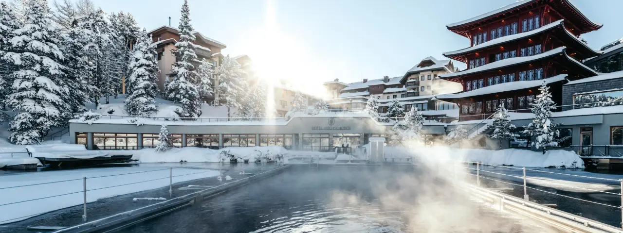 Beheizter Aussenpool mit Dampf im verschneiten Hotel Hochschober. Winterlandschaft und einzigartige Architektur am See.