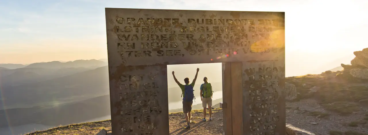 Wandererpaar genießt den Panoramablick auf den Millstätter See und die Berge im Sonnenuntergang nahe der Villa Postillion am See.