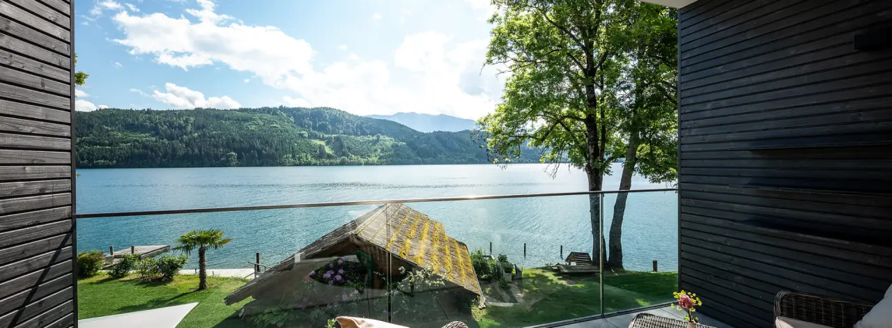 Balkonblick auf den Wörthersee und die umliegende Natur vom modernen Hotel Villa Postillion am See.