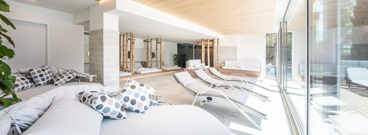 Heller Spa-Ruhebereich mit modernen Liegen, Tagesbetten und Blick ins Grüne in der Villa Postillion am See.