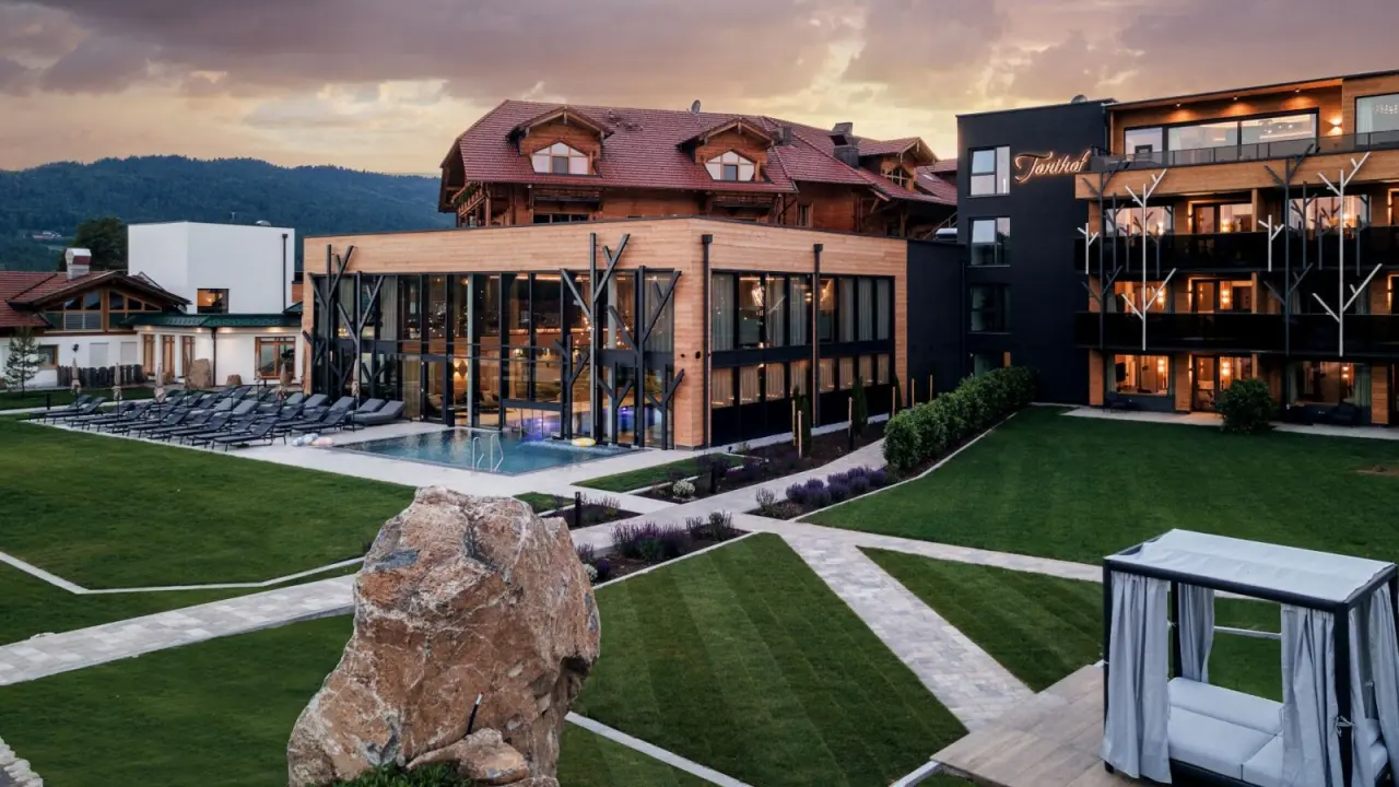 Abendansicht des Wellness & Naturhotel Tonihof mit beleuchtetem Aussenbereich, Pool und moderner Architektur.