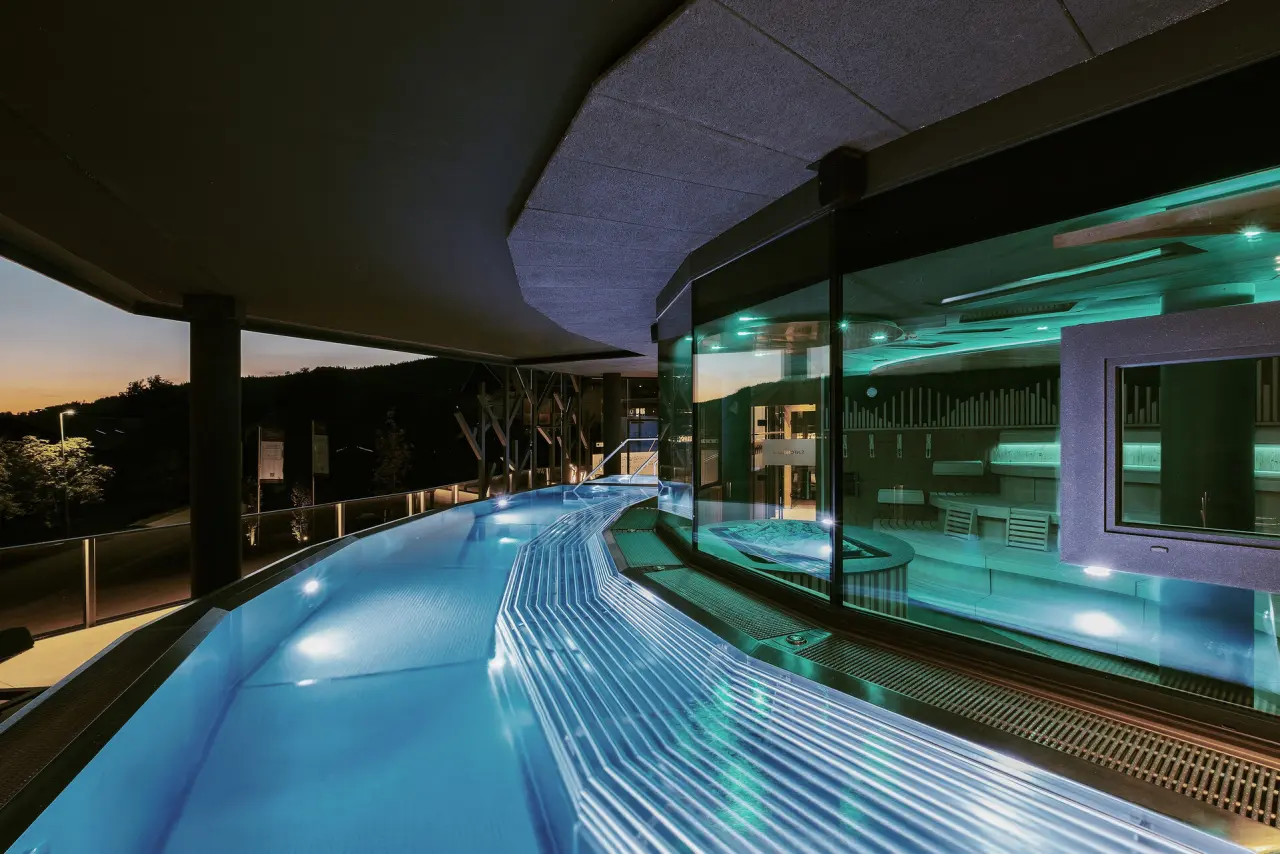 Beheizter Infinity-Pool mit Blick auf die Natur und integriertem Whirlpool im Wellness & Naturhotel Tonihof**** bei Sonnenuntergang.