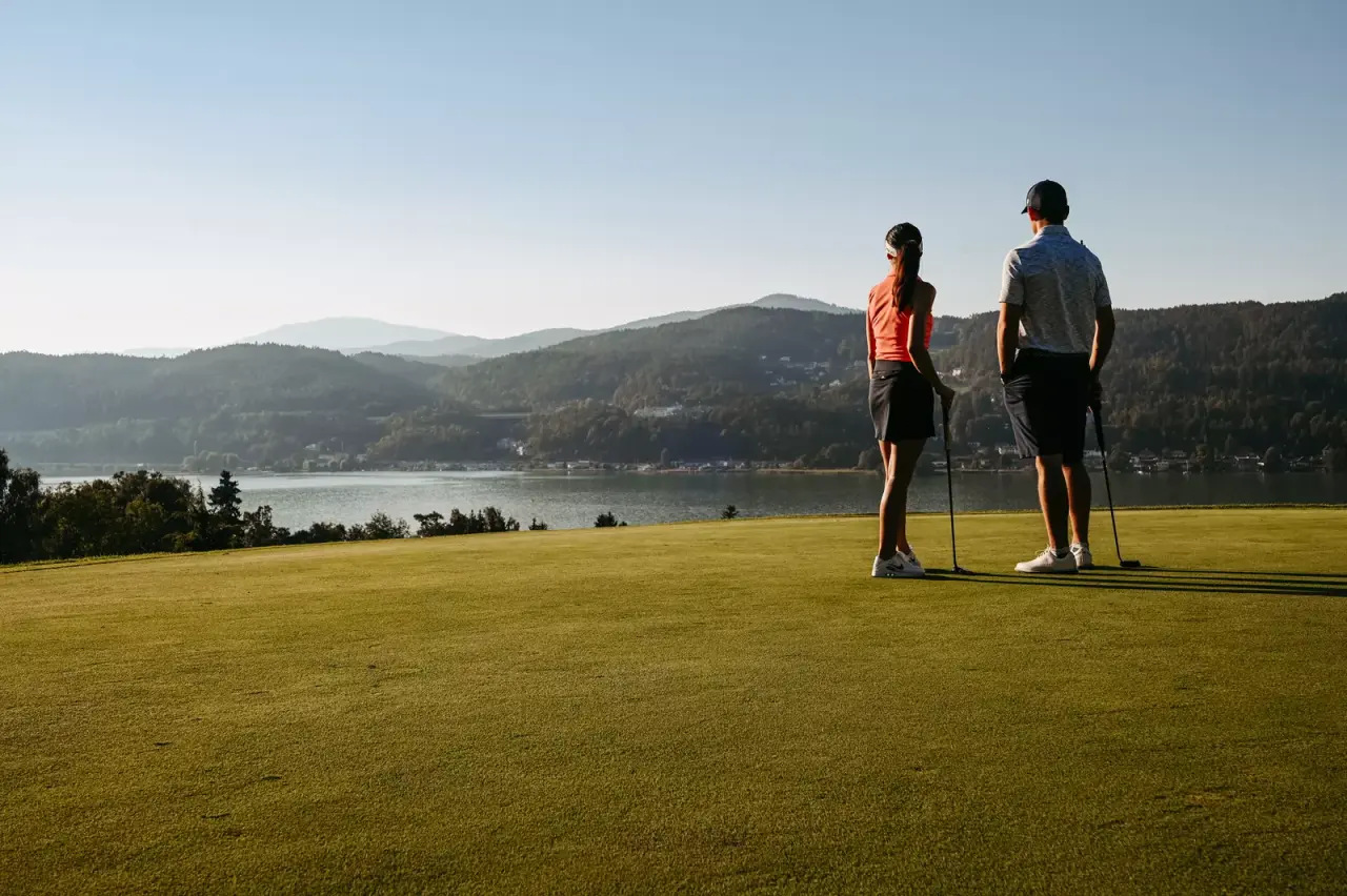 Zwei Golfer blicken auf den Wörthersee und die umliegenden Berge vom Golfplatz des Seehotel Europa.