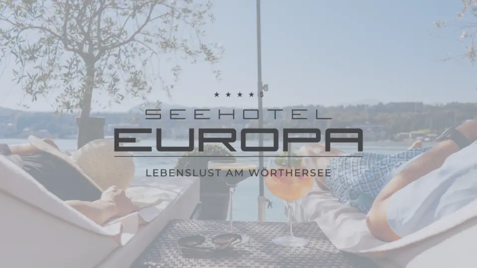 Zwei Personen entspannen auf Liegen am Ufer des Wörthersees mit Cocktails im Seehotel Europa.