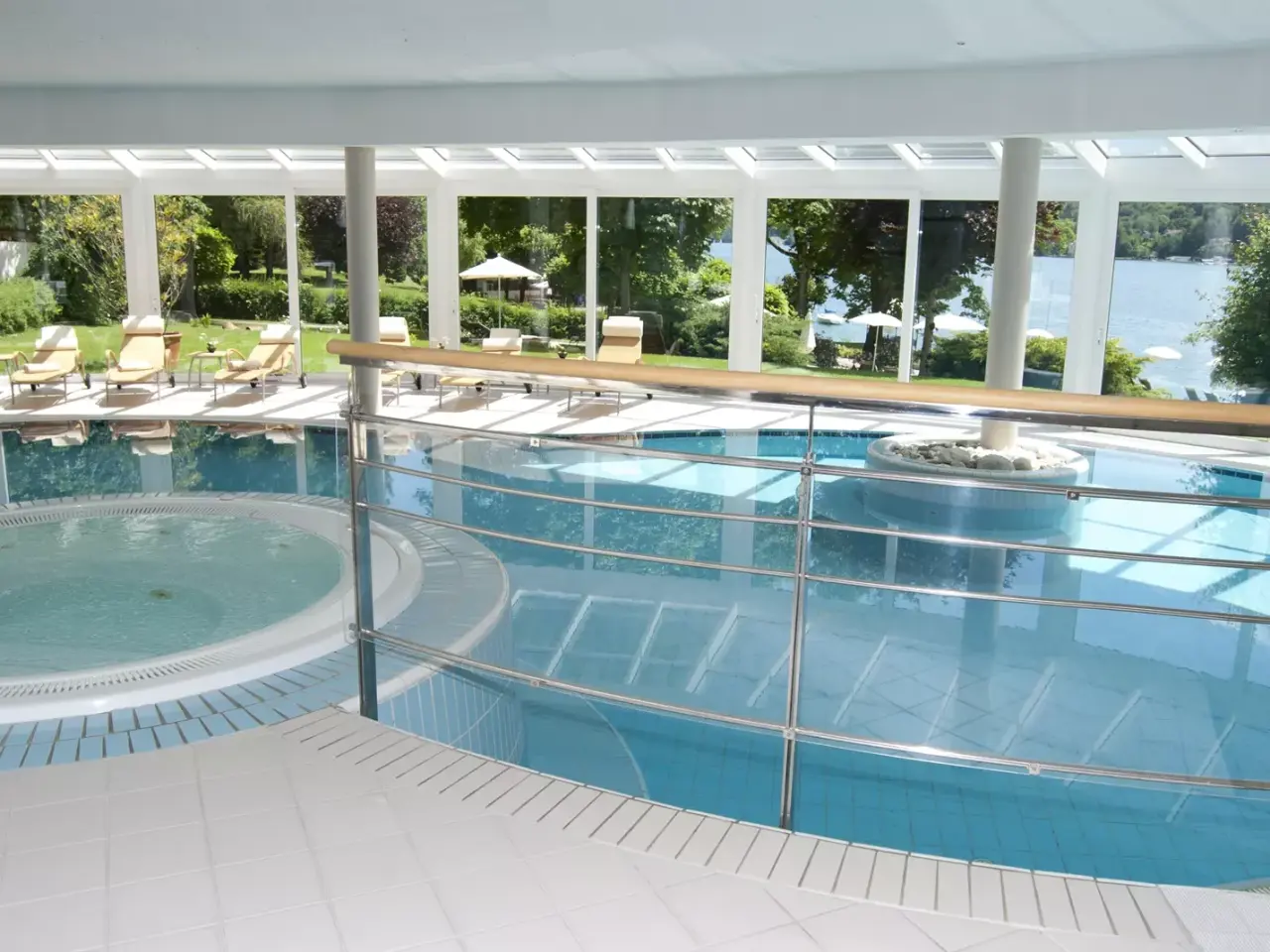 Großzügiger Innenpool mit Whirlpool und Panoramablick auf den See und die grüne Gartenanlage im Seehotel Europa.