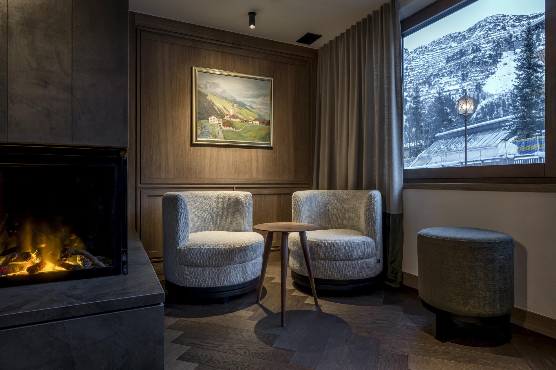 Hotel Auenhof in Lech am Arlberg – Gemütliche Sitzecke mit Kamin und Bergblick | Wellnesshotel Arlberg