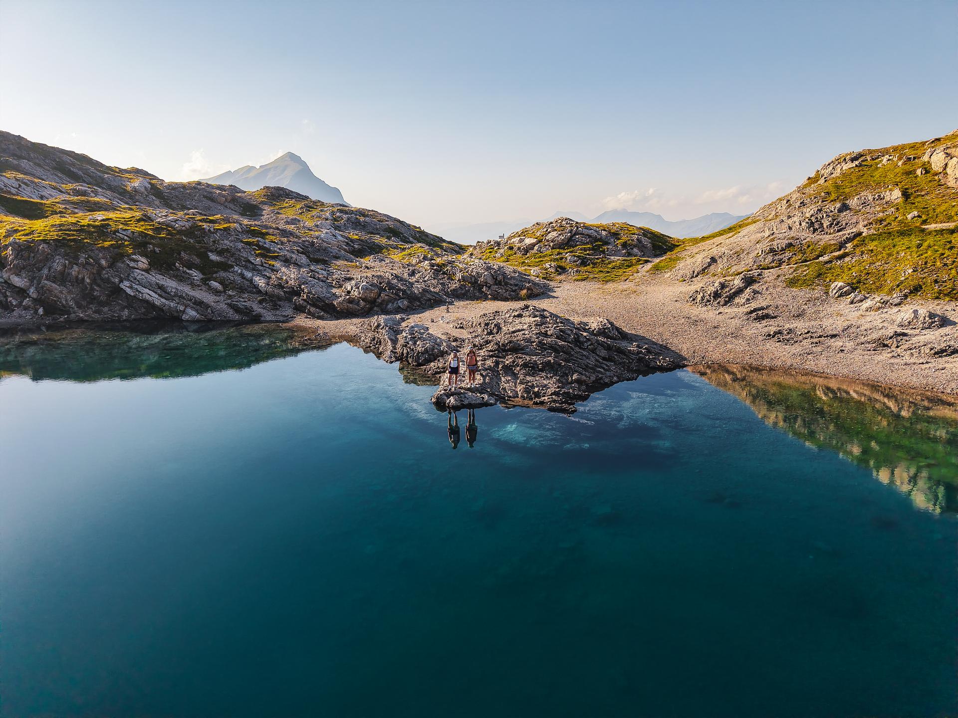 Hotel Auenhof in Lech am Arlberg – Malerischer Bergsee mit Felsen und Wanderern | Wellnesshotel Arlberg