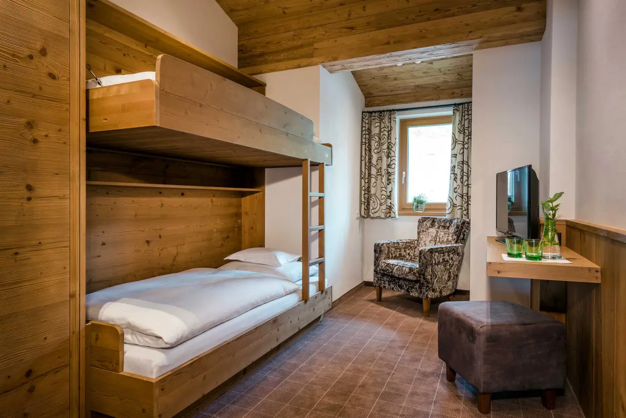 Gemütliches Familienzimmer mit Etagenbett und Holzelementen im Hotel Auenhof, ideal für einen Aufenthalt mit Kindern.