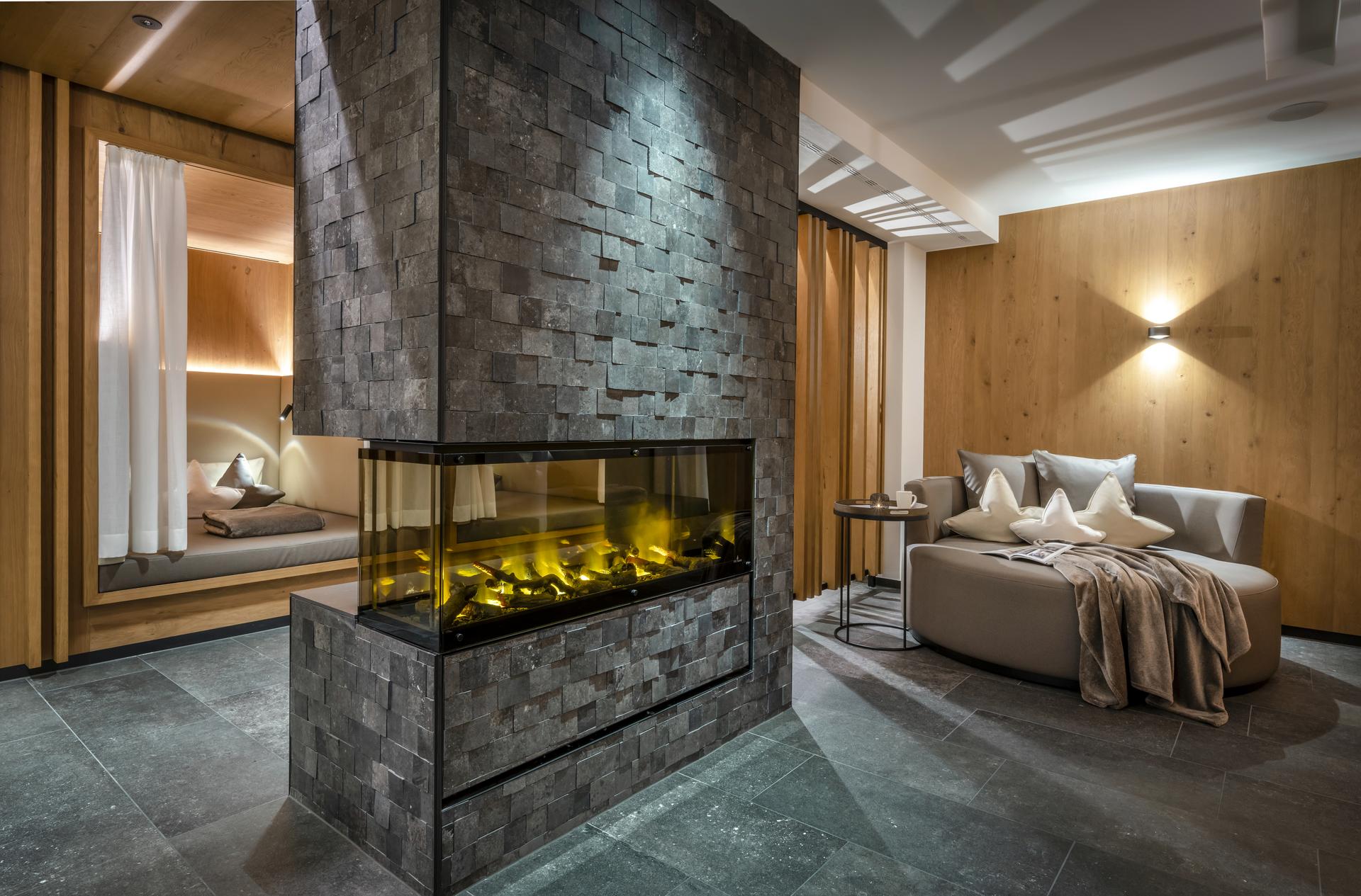 Hotel Auenhof in Lech am Arlberg – Entspannungsbereich mit Kamin und bequemen Liegen | Wellnesshotel Arlberg