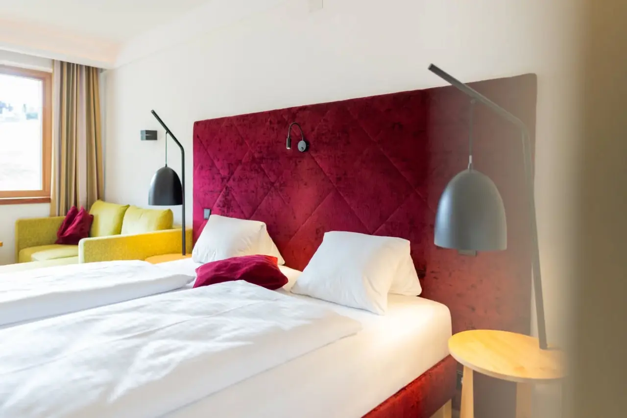Gemütliches Doppelzimmer mit rotem Kopfteil und gelbem Sofa im Hotel NockResort
