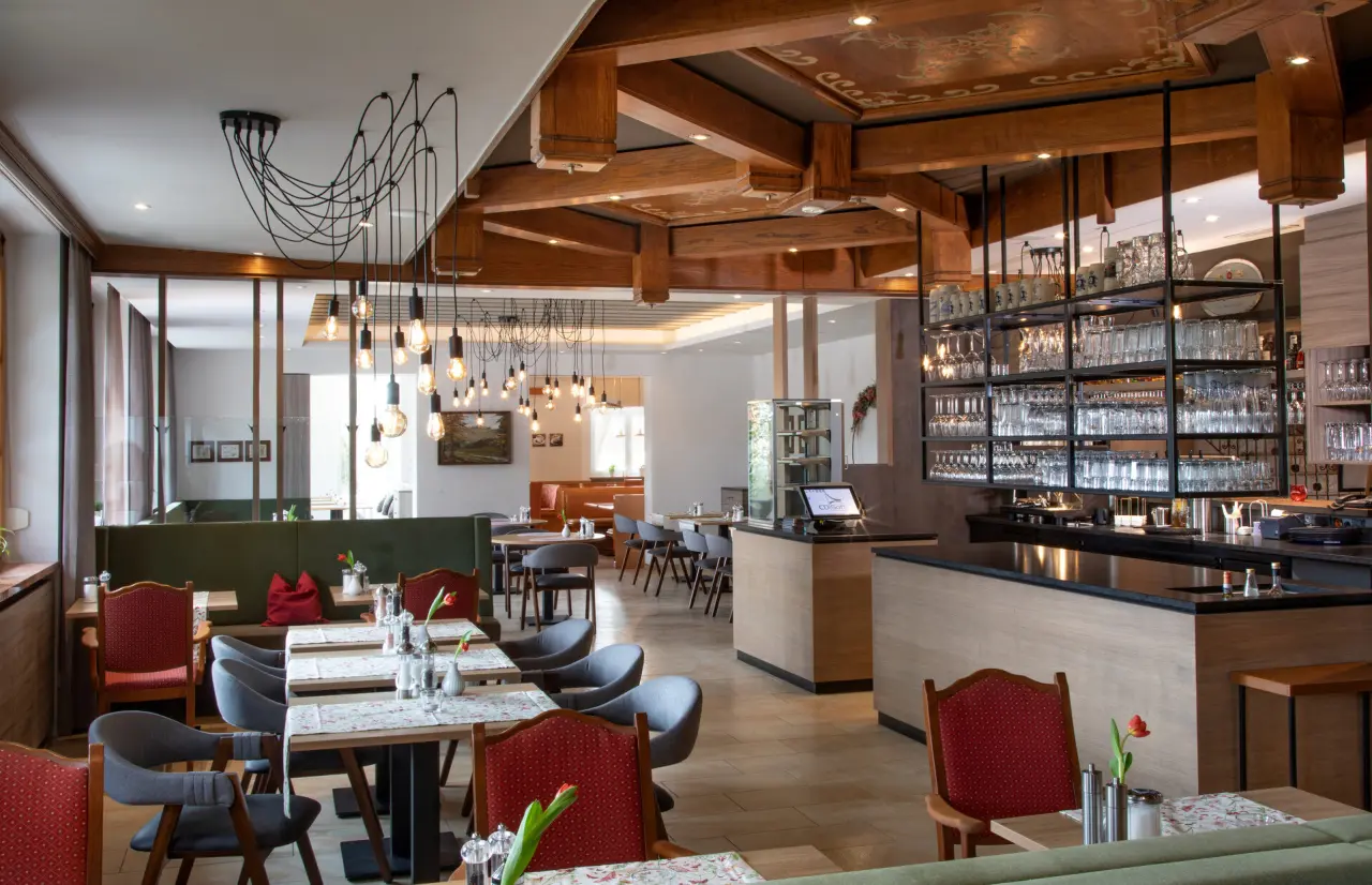 Gemütliches Restaurant im Hotel Quellenhof mit Holzbalken, modernen Leuchten und einladenden Sitzbereichen.