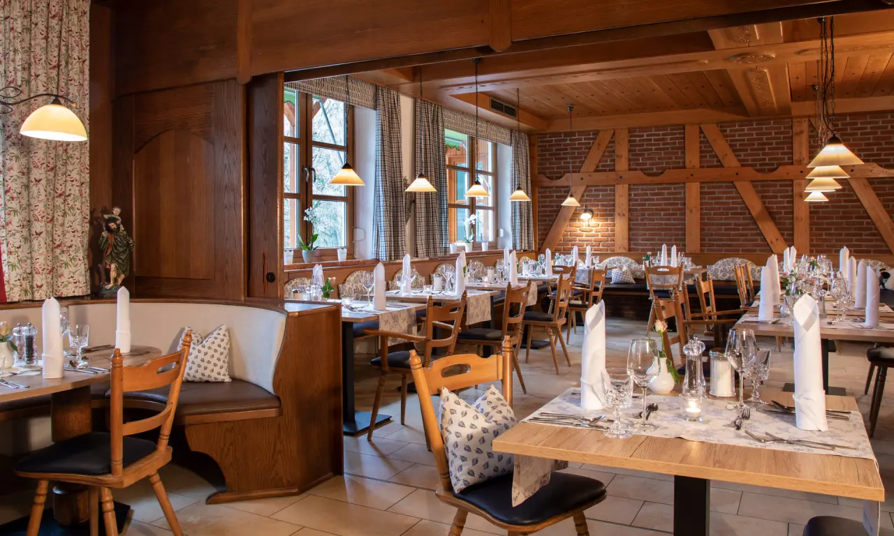 Gemütliches Restaurant im traditionellen Stil mit Holzelementen und Backsteinwand im Hotel Quellenhof, einladend gedeckte Tische.