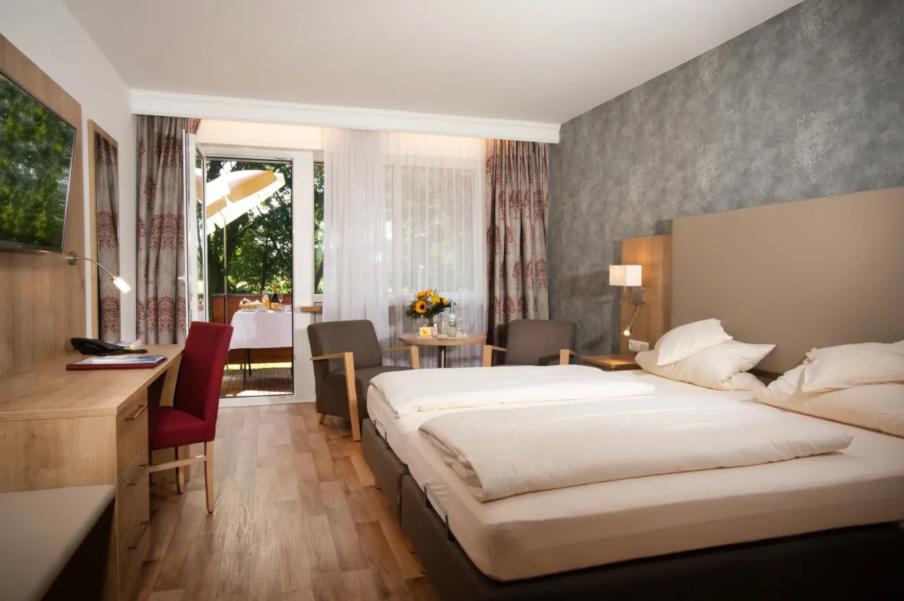 Gemütliches Doppelzimmer mit Balkon und Blick ins Grüne im Hotel Quellenhof.
