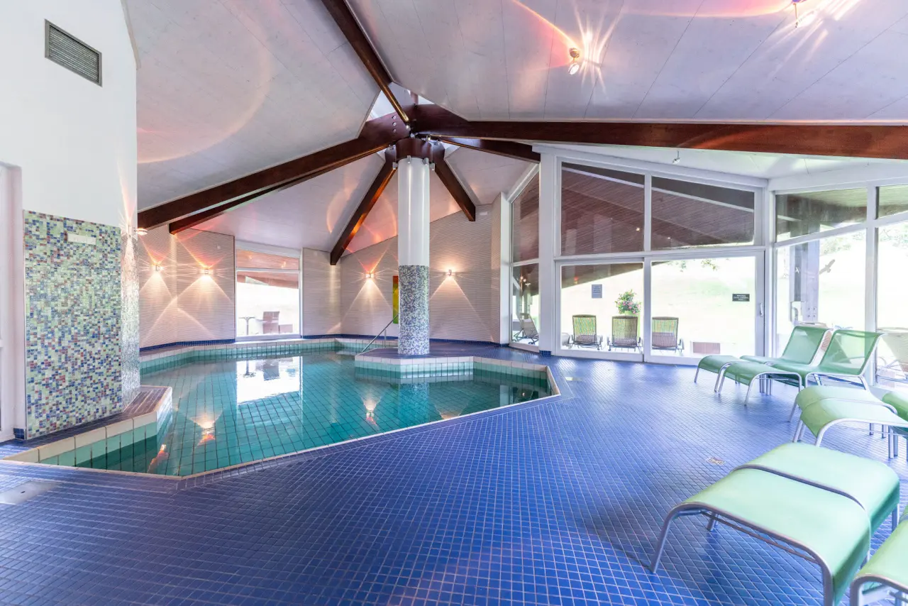 Heller Innenpoolbereich mit grossen Panoramafenstern und Liegestühlen im Hotel Ochsen Schönwald.