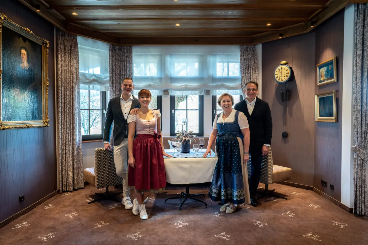 Gastgeberfamilie des Hotel Ochsen Schönwald in traditioneller Kleidung im gemütlichen Restaurantbereich mit gedecktem Tisch.