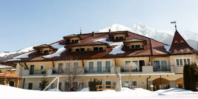 Winterliche Aussenansicht des Wellnesshotel Schönruh mit verschneitem Dach und majestätischen Bergen im Hintergrund.