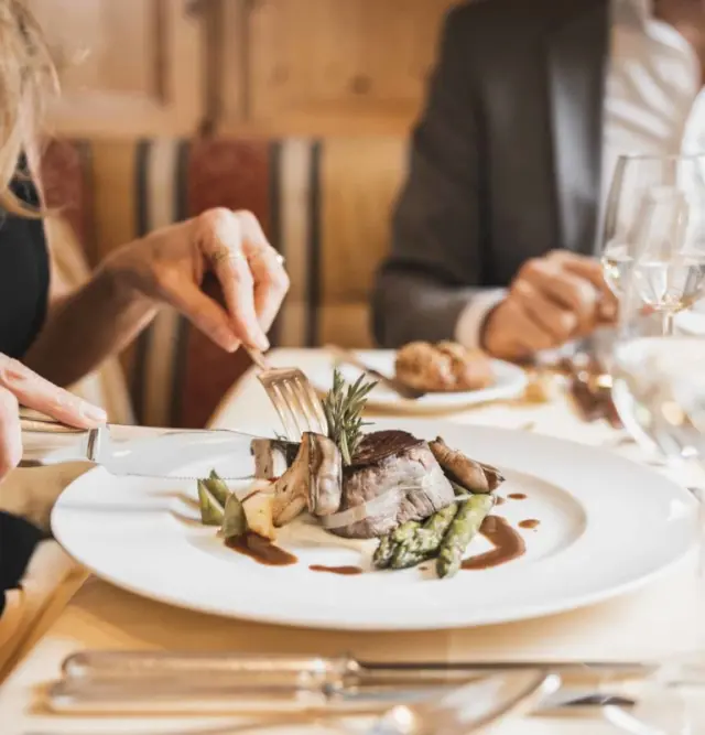 Gast genießt ein exquisites Abendessen mit Fleisch und Spargel im Restaurant des Wellnesshotel Schönruh.