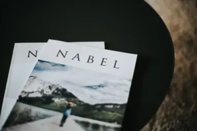 Zwei Magazine mit dem Titel 'NABEL' auf einem dunklen Tisch im Hotel DIE WASNERIN.