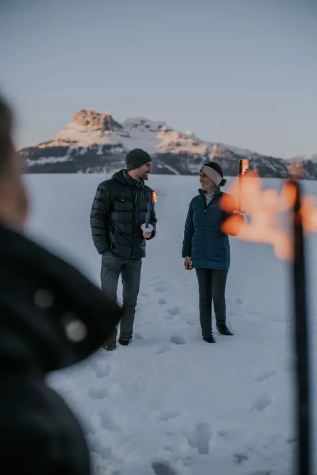 Paar bei Fackelwanderung im Schnee mit Bergpanorama im Hintergrund, Hotel DIE WASNERIN.
